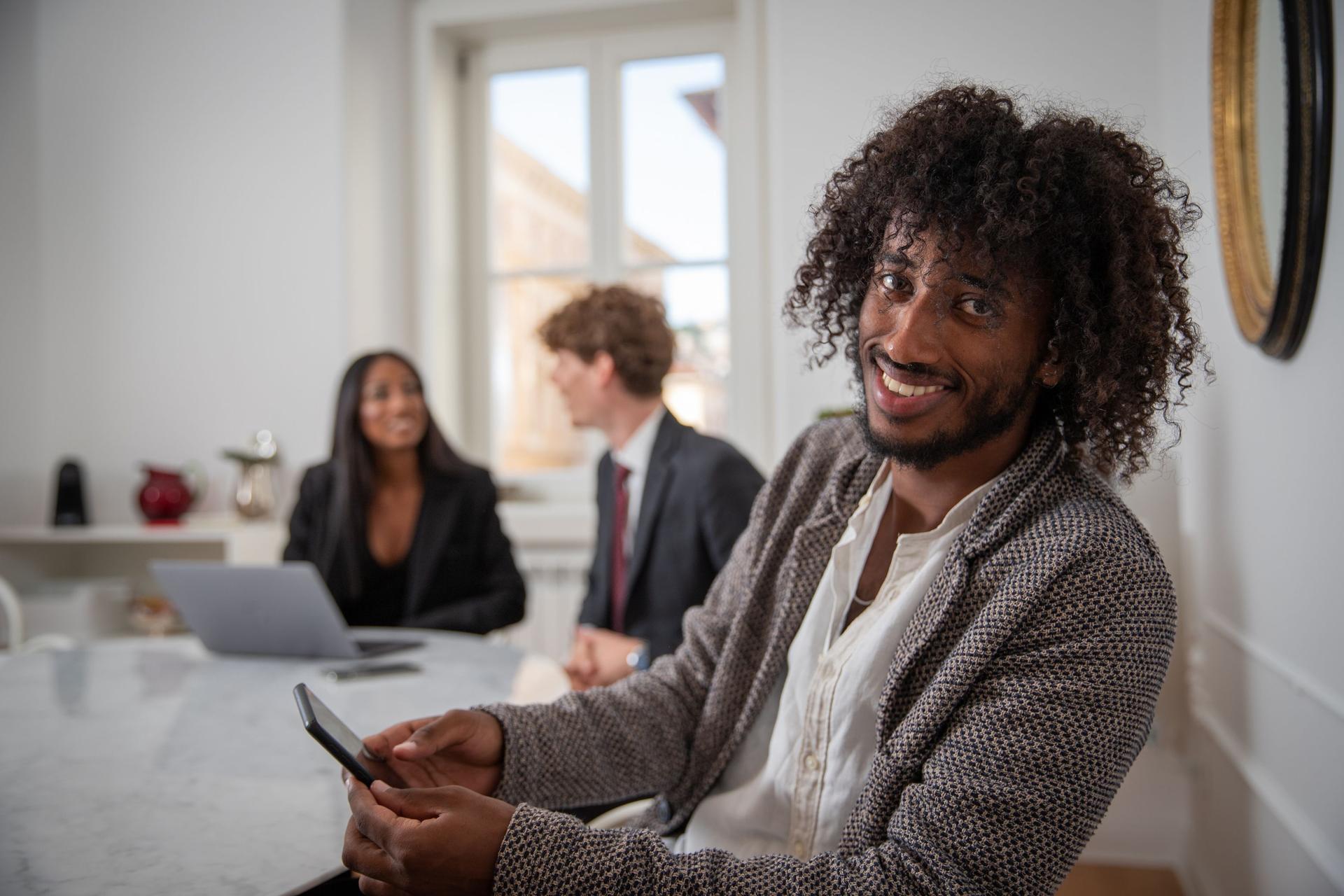 A group of young business people during a meeting, close up on young African entrepreneur smiling.